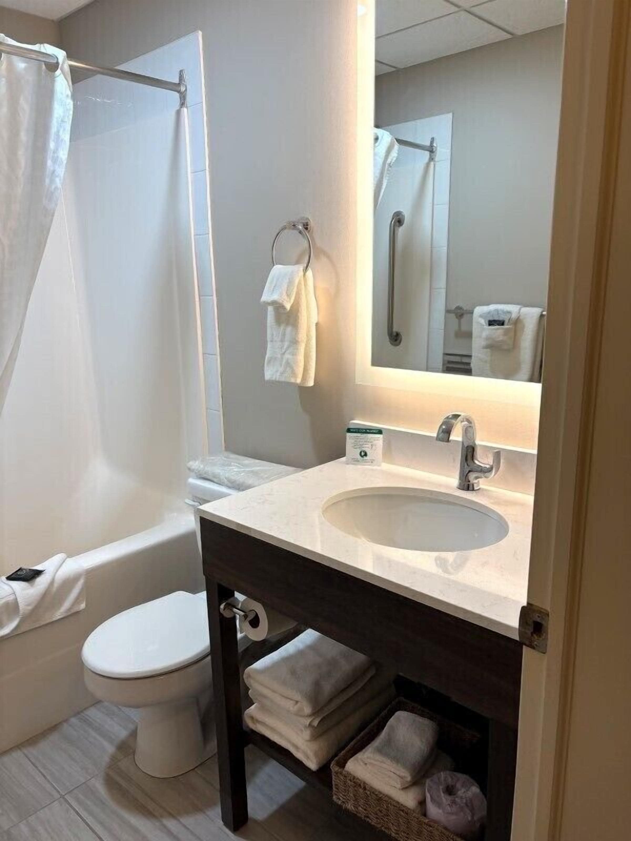A bathroom with a bathtub, toilet, sink, and a mirror.