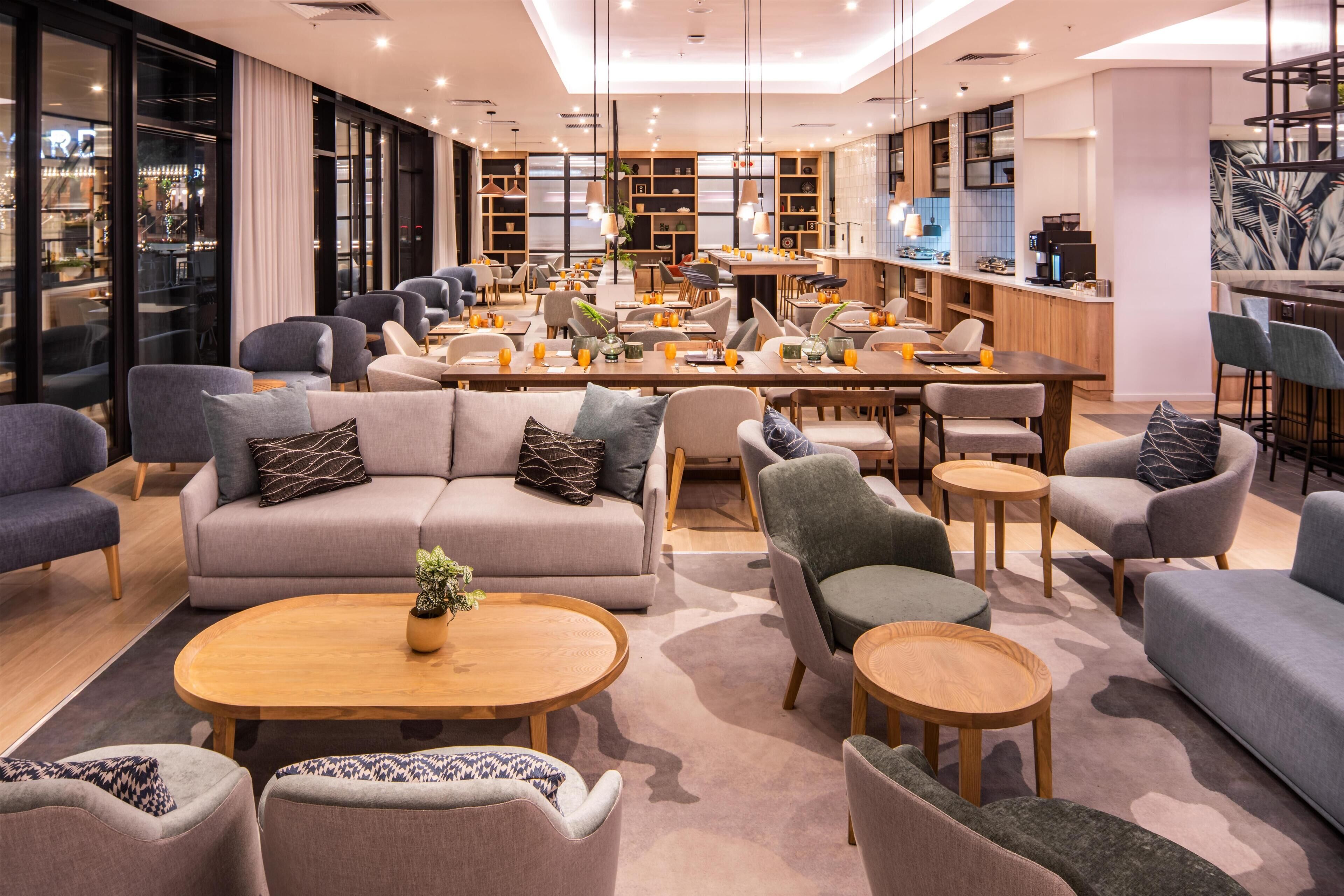 Un moderno vestíbulo de hotel con zonas de estar, un bar y una cocina a la vista.