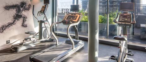 Een sportschool met loopbanden, hometrainers en een muur met motiverende teksten.