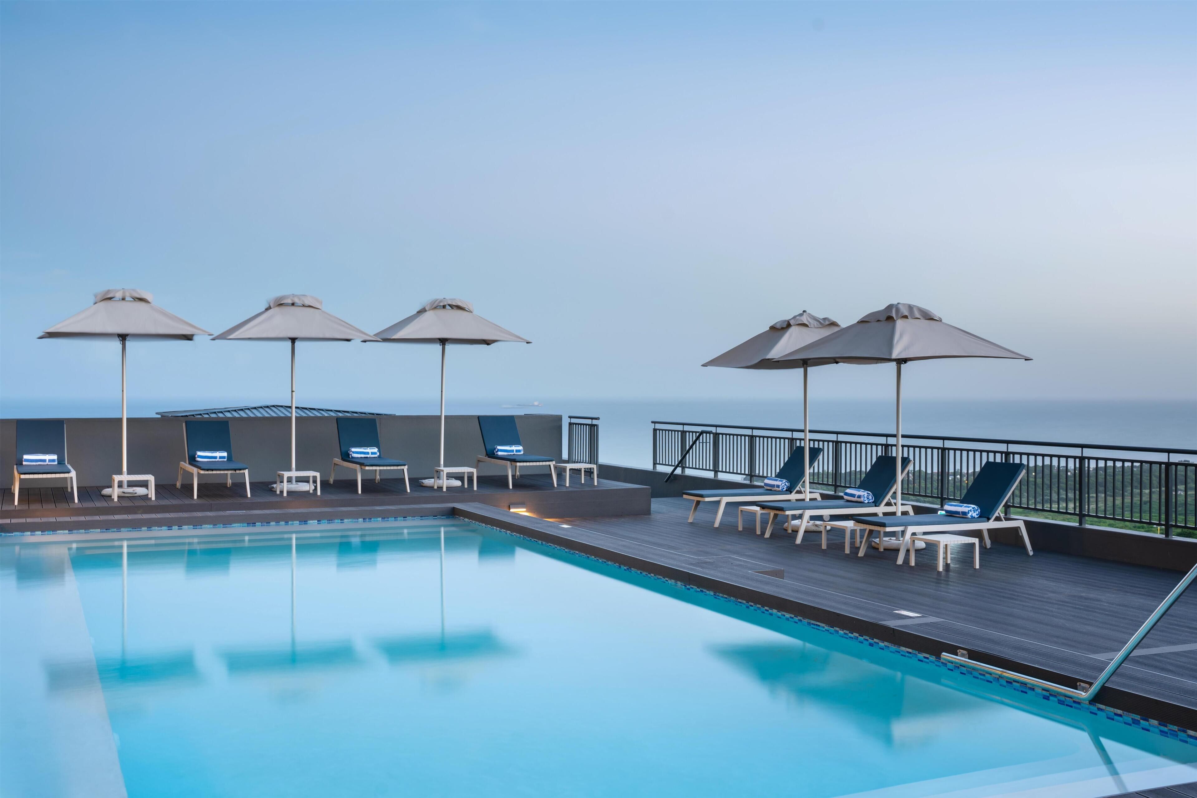 Een buitenzwembad, parasols voor strand/zwembad