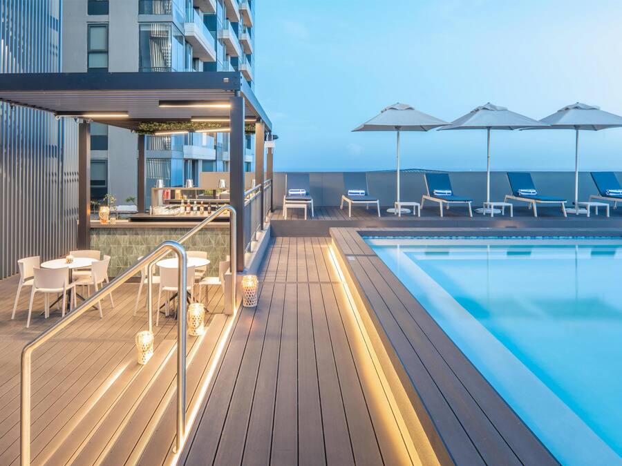 Een buitenzwembad, parasols bij het zwembad en ligstoelen