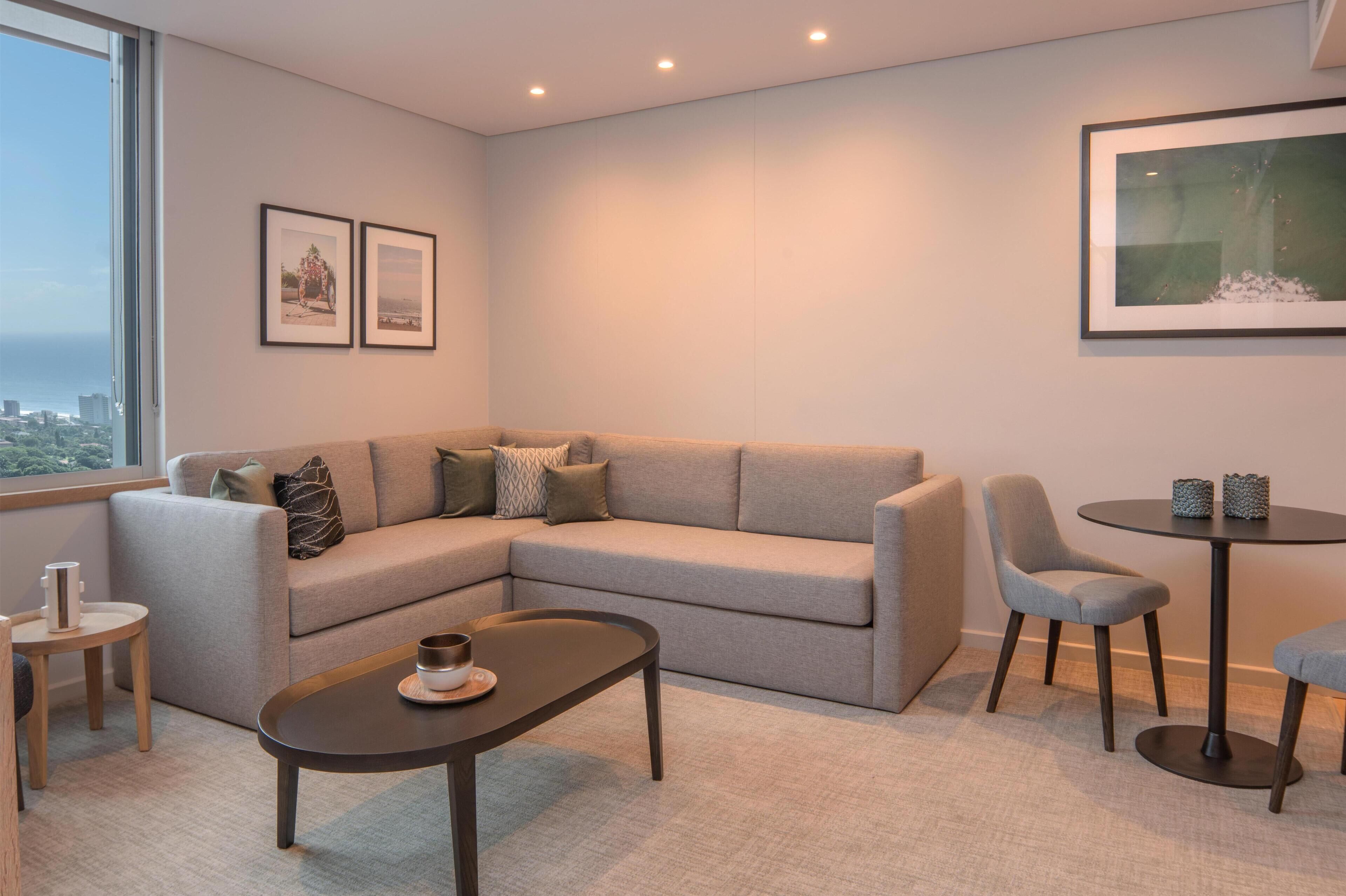 A modern living room with a sofa, a coffee table, and a small round table with two decorative items.