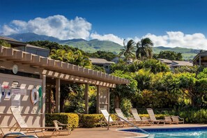 Ein Poolbereich mit Liegestühlen, einer Pergola und Blick auf die Berge.