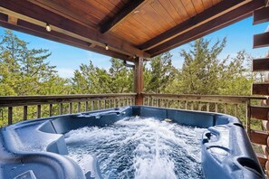 A hot tub with a wooden deck and railing, surrounded by trees. - Still Water Hideaway: Calm Waters, Quiet Escapes (Sevierville)