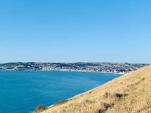 Une ville côtière offrant une vue dégagée sur la mer et dont le paysage est dominé par des collines en arrière-plan.