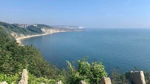 A coastal landscape with a clear view of the sea, a sandy beach, and a cliff with buildings on top. - Charming 3-bed Cottage in Swanage (Swanage)