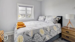 A bedroom with a bed, a window, a bedside table, and a lamp. - Charming 3-bed Cottage in Swanage (Swanage)