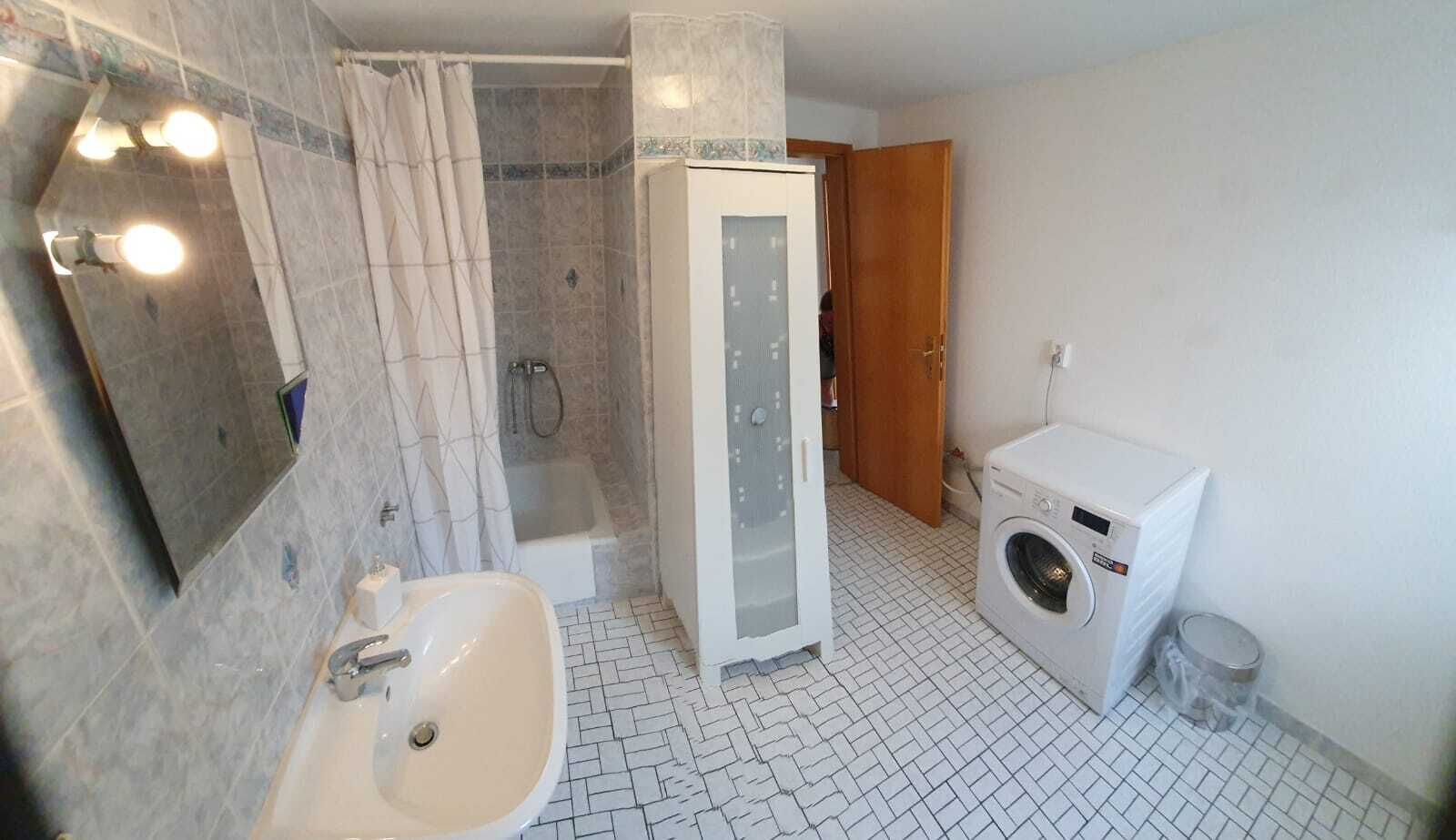 A bathroom with a shower, a sink, a toilet, and a washing machine.
