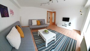 Una sala moderna con un sofá gris, una mesa de centro blanca y una alfombra a rayas.