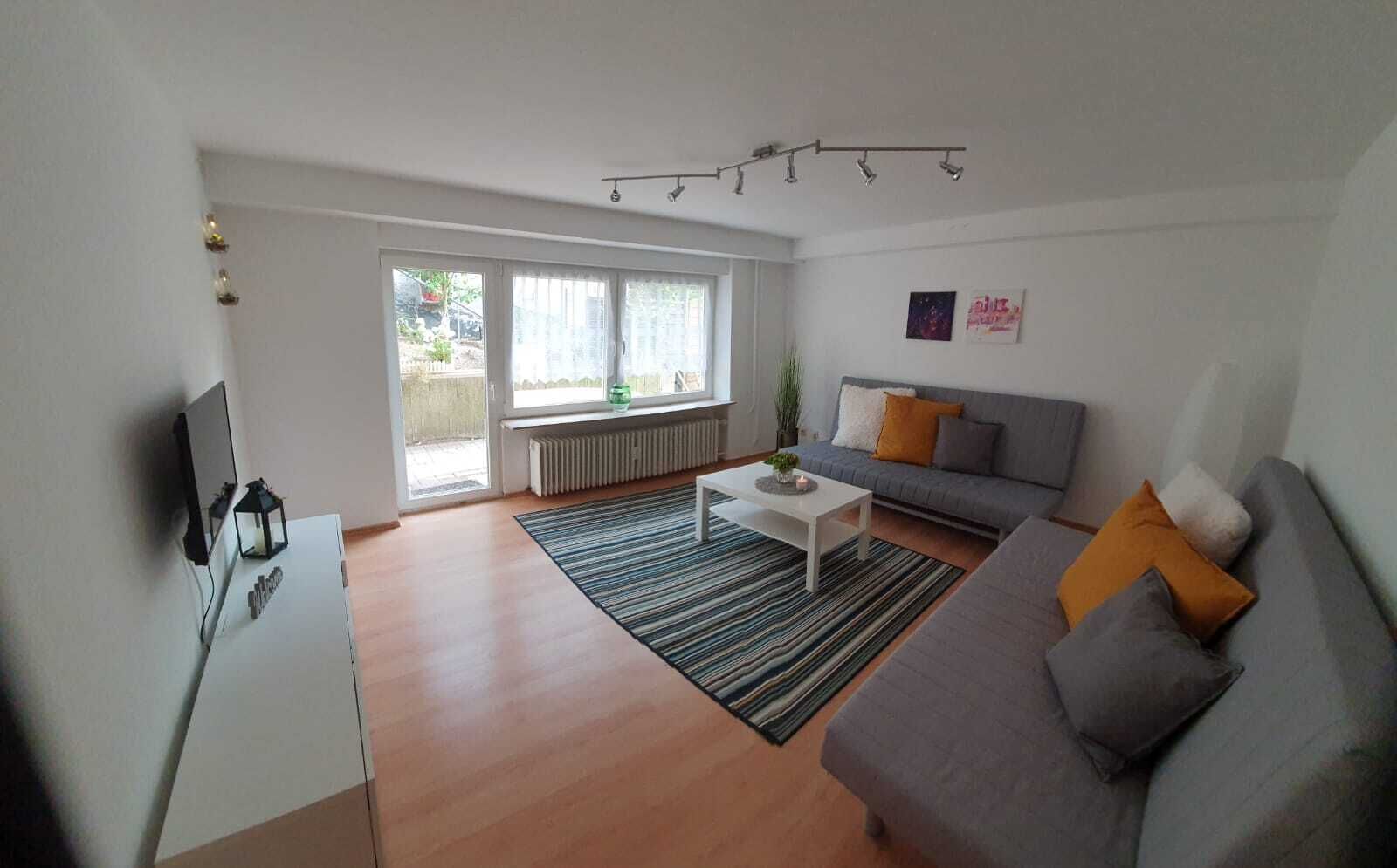 Una sala de estar moderna con un sofá gris, una mesa de centro blanca y una alfombra a rayas.