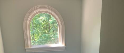 A bathroom with a freestanding bathtub, a toilet, and a window with a view of greenery.