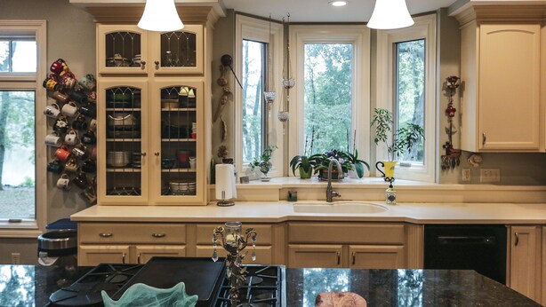 A kitchen with two pendant lights, a built-in wine rack, a sink, and a window with a view of trees. - Beautiful Charlotte Lake Wylie Waterfront Bungalow (Charlotte)