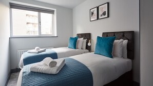 A hotel room with two beds, a large window, and a radiator.