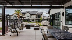 Un espace extérieur aménagé en terrasse, avec un coin salon abrité, une table et un barbecue.