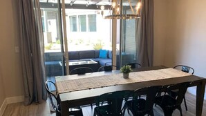 Un espace repas avec une longue table, des chaises et un lustre.