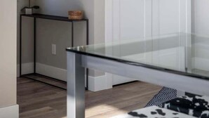 Une pièce moderne avec une table en verre, une porte blanche et un miroir décoratif.