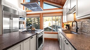 A modern kitchen with stainless steel appliances, a large window, and a skylight.