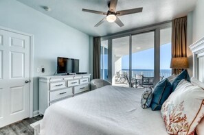 Relax in this serene room with a large bed, ceiling fan, and ocean views from the balcony.