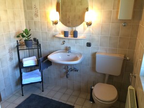 Une salle de bain équipée d’un lavabo, de toilettes et d’un porte-serviettes.