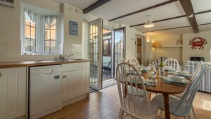 Une cuisine équipée d’un lave-vaisselle, d’une table à manger pour quatre personnes et offrant une vue sur l’extérieur grâce à une porte vitrée.