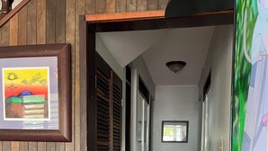 A hallway with wooden walls, a tiled floor, and a framed picture on the left.