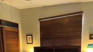 A bedroom with a bed, bedside lamps, a bench, a ceiling fan, and a wooden wardrobe.