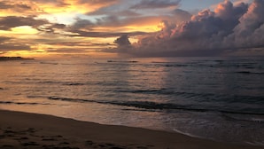 A beach with waves and a sunset.
