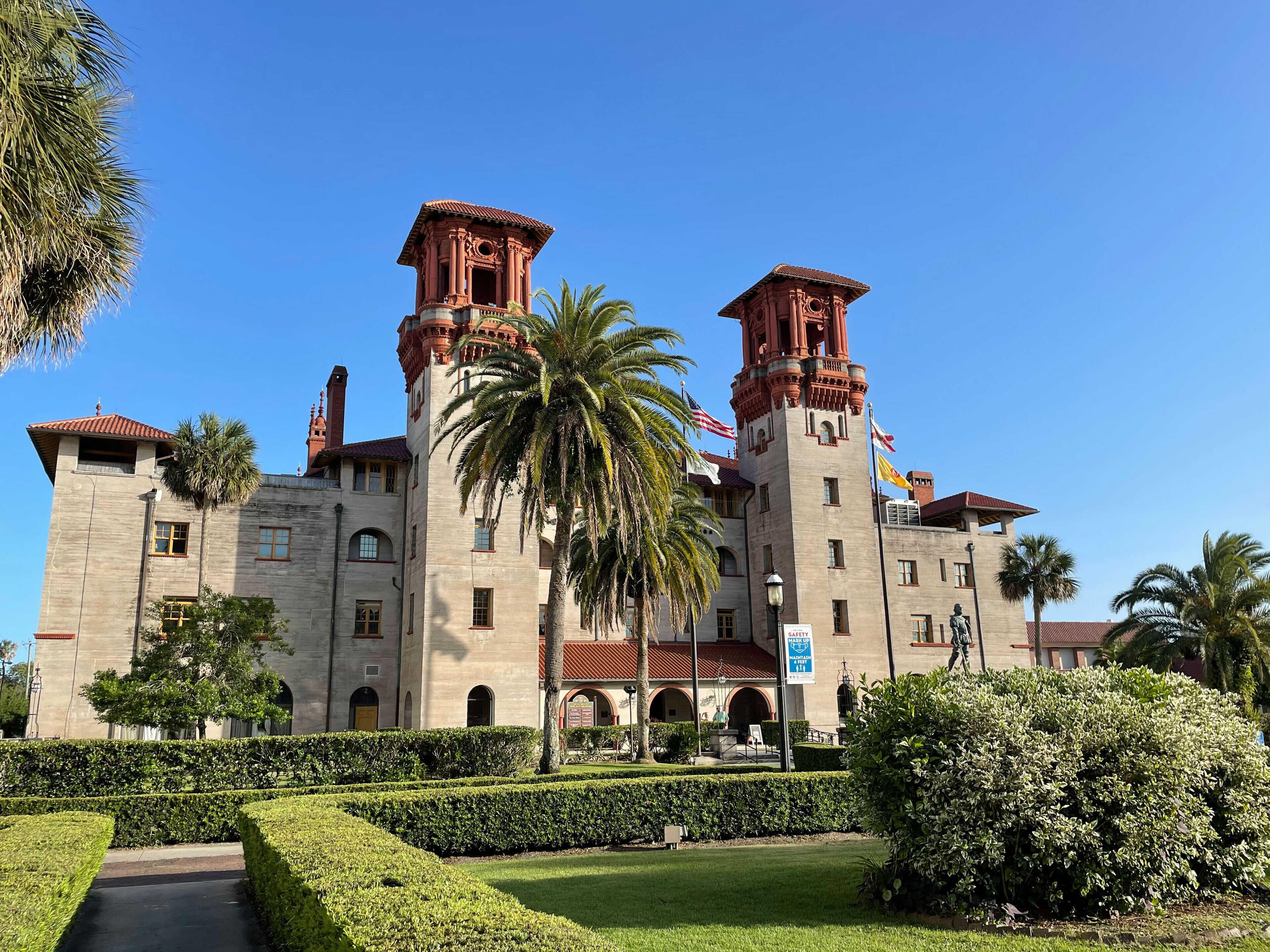 A historic building with two prominent towers, a central courtyard, and well-maintained landscaping.