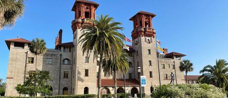 A historic building with two prominent towers, a central courtyard, and well-maintained landscaping.