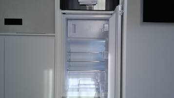 Eine moderne Küche mit einem integriertem Kühlschrank, einer Mikrowelle und einem Spülbecken.