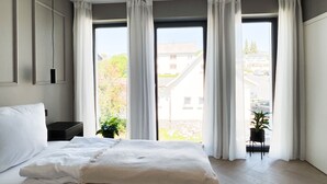 Een moderne slaapkamer met een groot bed, een nachtkastje en een potplant.