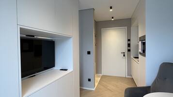 Un salon moderne et minimaliste, doté d’un téléviseur encastré, d’un canapé gris et d’une table à manger.