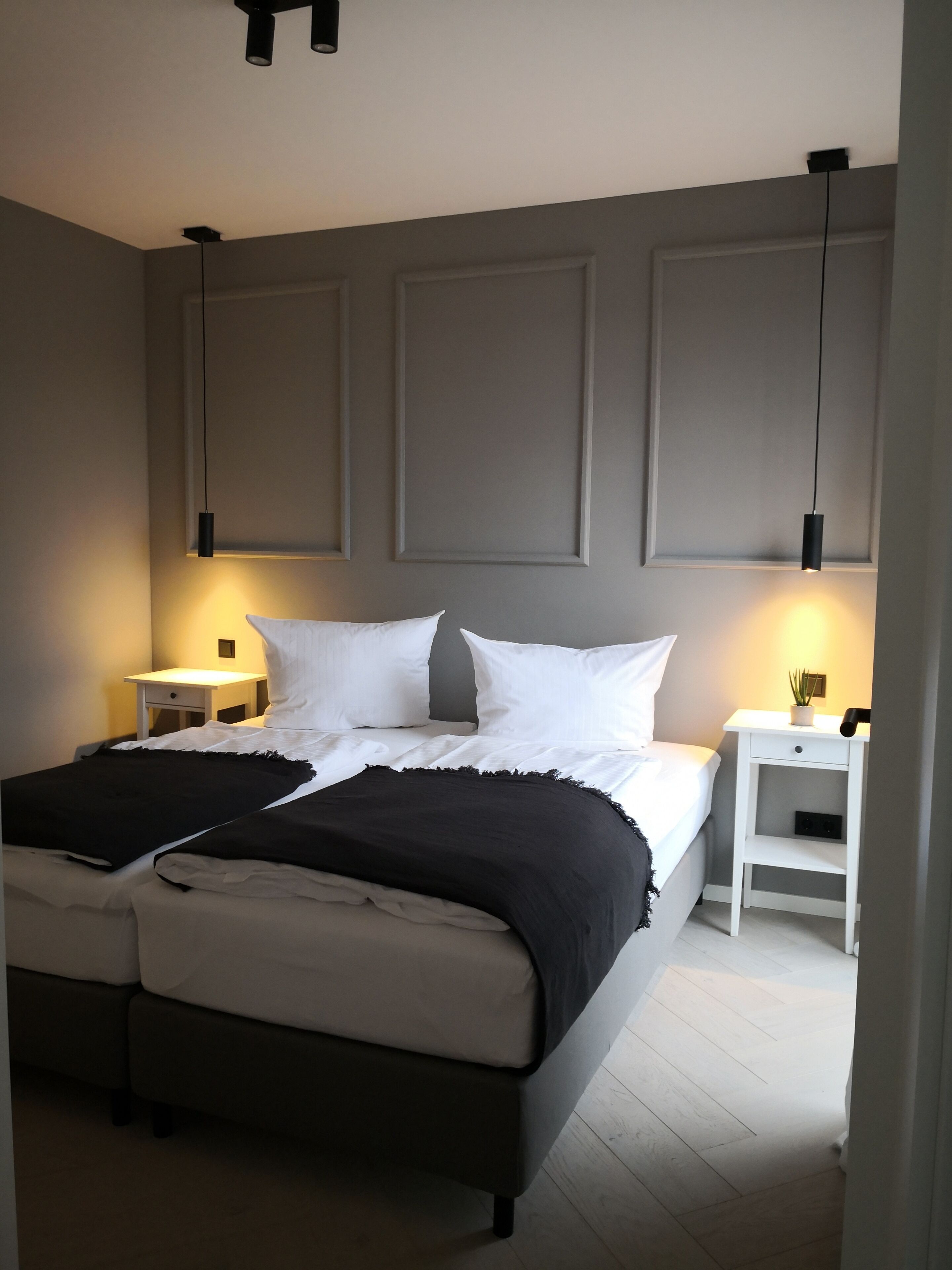 Une chambre à coucher avec un grand lit, deux tables de chevet et un luminaire fixé au plafond.