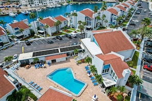 A hotel with a swimming pool, a marina with boats, and a parking lot. - Pickleball, Pools & Docks - Yacht Club #165A (Madeira Beach)