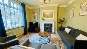 Ein Wohnzimmer mit Kamin, einer Couch, einem Fernseher und einem Couchtisch.
