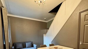 En kompakt opholdsstue med spisebord, stole, sofa og trappe.