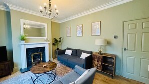 Ein Wohnzimmer mit Kamin, Sofa, Couchtisch und einer Chandelier.