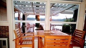A wooden table and chairs set up under a pergola with a view of a body of water and hills. - STUNNING  Lakefront,  Huge DOCK,2 Kayaks, Sleep 8, Prime fishing spot (Clearlake Oaks)