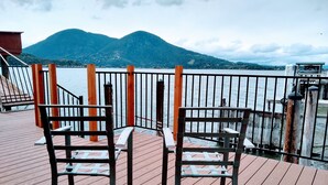 A wooden deck with two chairs facing a body of water and mountains in the background. - STUNNING  Lakefront,  Huge DOCK,2 Kayaks, Sleep 8, Prime fishing spot (Clearlake Oaks)