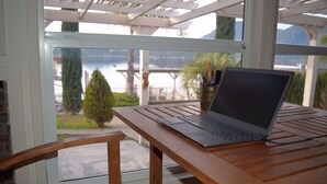 A laptop on a wooden table with a view of a lake and mountains. - STUNNING  Lakefront,  Huge DOCK,2 Kayaks, Sleep 8, Prime fishing spot (Clearlake Oaks)