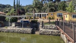 A lakeside property with a gazebo, a stone wall, and a yellow building. - STUNNING  Lakefront,  Huge DOCK,2 Kayaks, Sleep 8, Prime fishing spot (Clearlake Oaks)