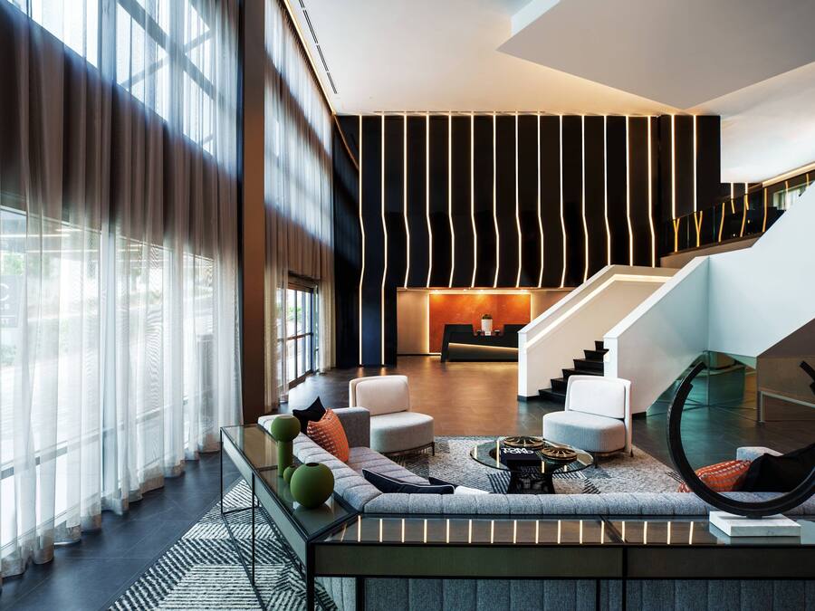 A modern lobby with a staircase, seating area, and a reception desk.