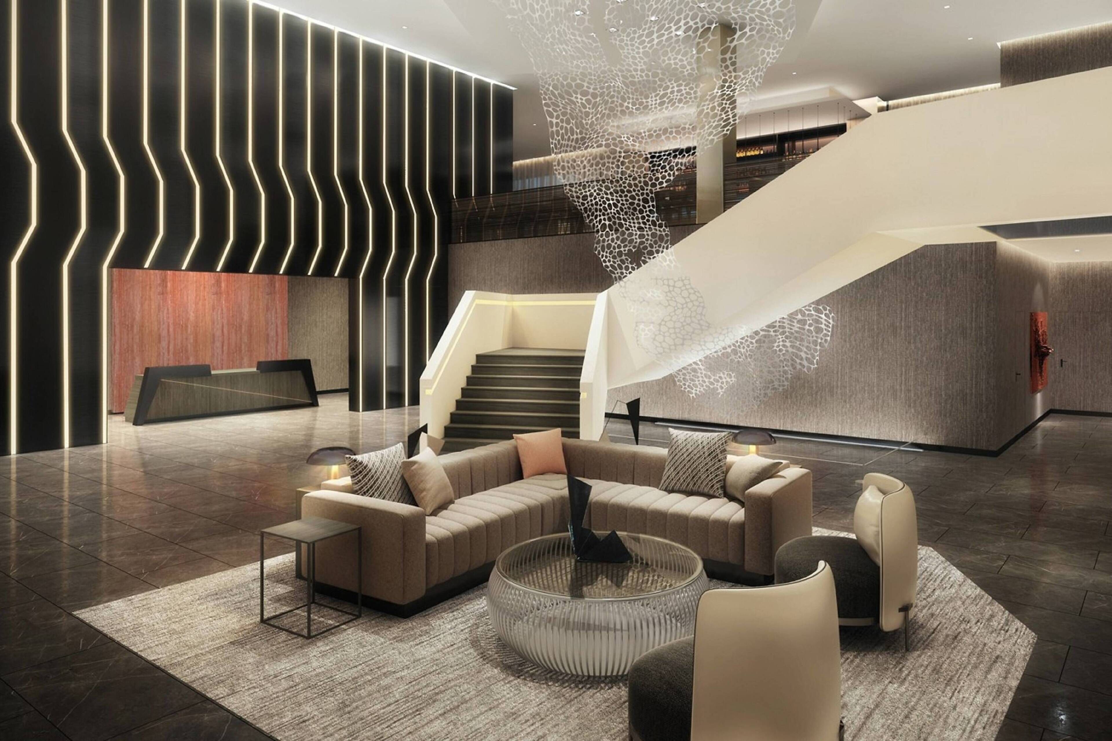 A modern lobby with a curved sofa, a round coffee table, and a staircase with a unique design.