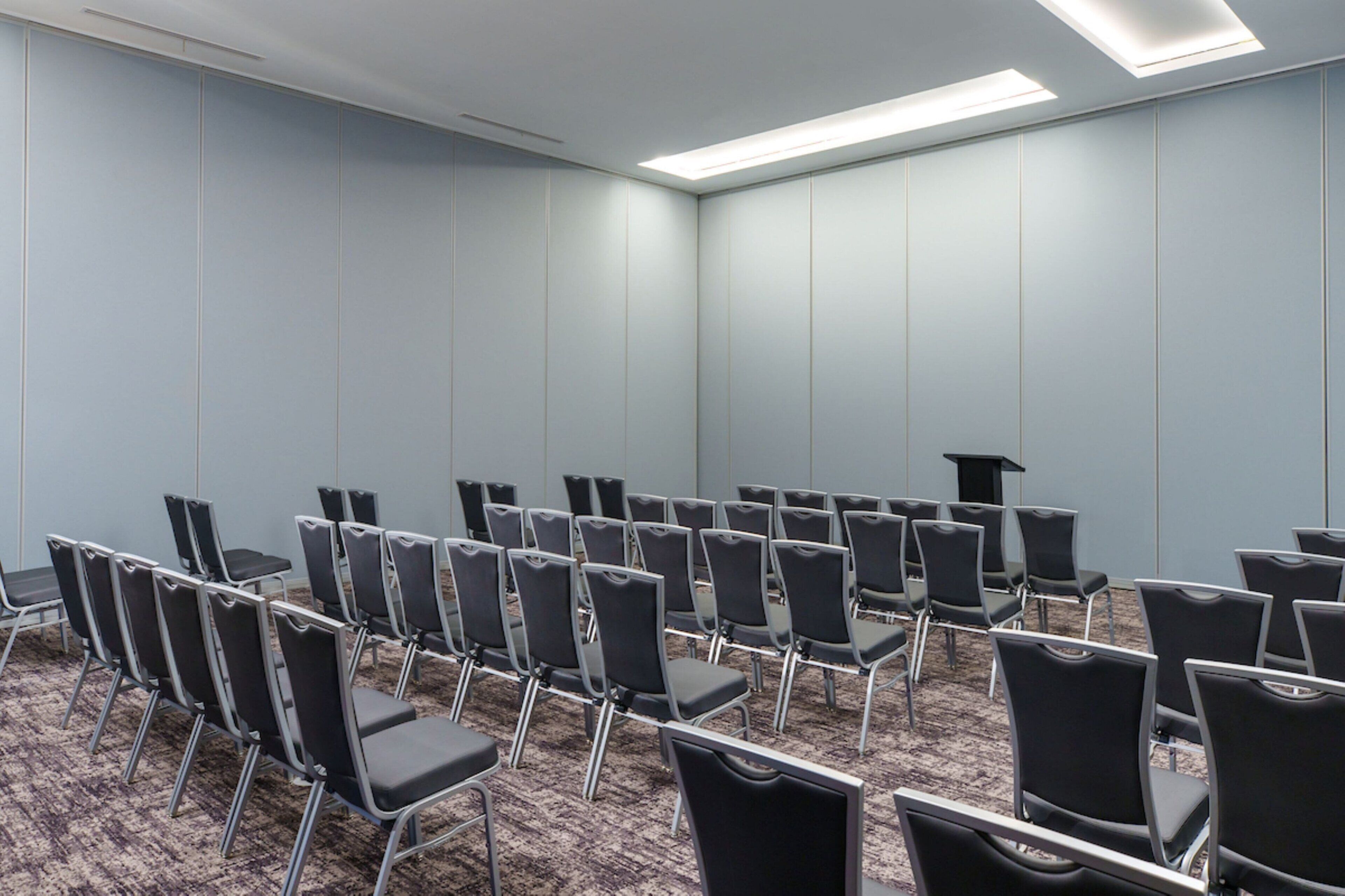 A conference room with rows of chairs and a podium.
