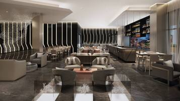 A modern hotel lobby with a central seating area, a bar, and a view of the cityscape.