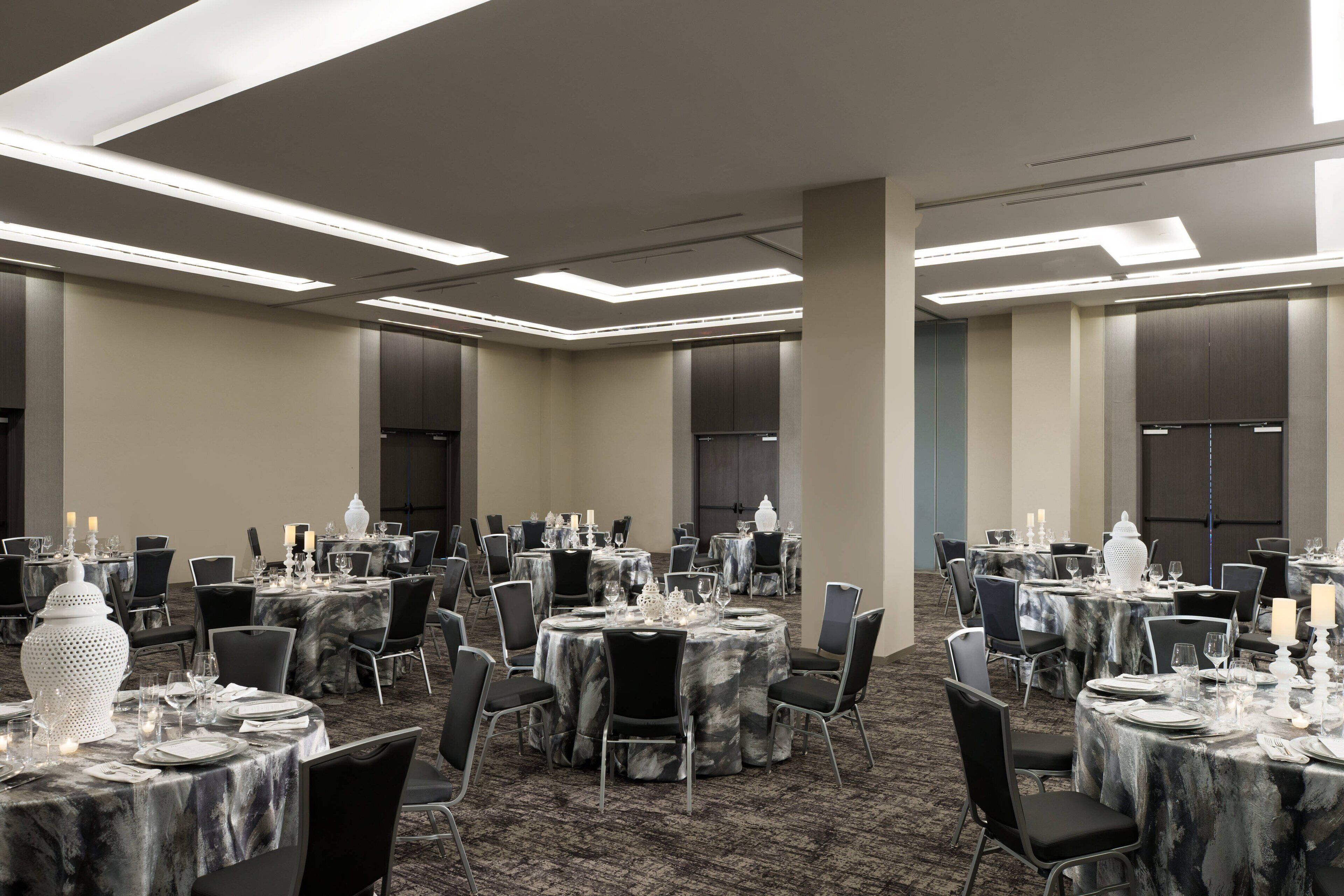 A conference room with multiple round tables, each set with chairs, candles, and decorative items.