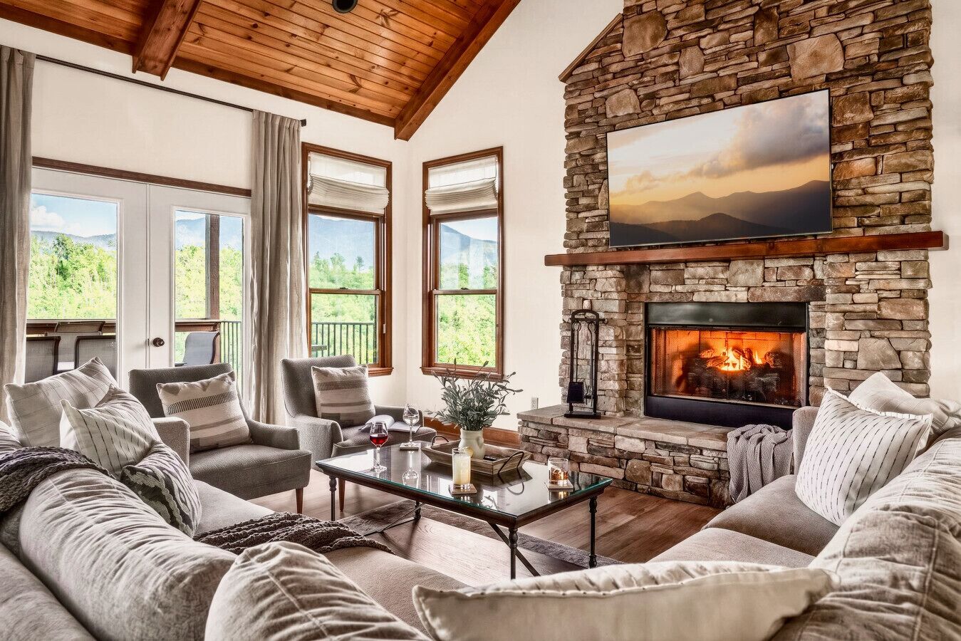 Una sala de estar acogedora con chimenea de piedra, asientos cómodos, ventanas amplias y una vista panorámica.
