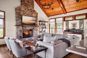 A living room with a stone fireplace, a large sofa, and a dining table.