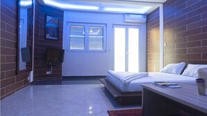 Une chambre d’hôtel avec un lit, un bureau, une chaise, une télévision et une fenêtre.