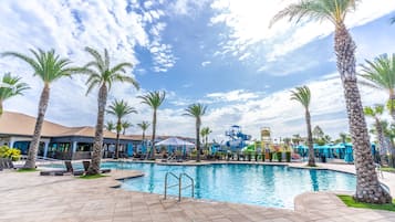 A swimming pool area with palm trees, lounge chairs, and a water slide.